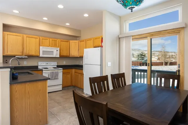 a kitchen with granite countertop a stove a refrigerator a dining table and chairs with wooden floor