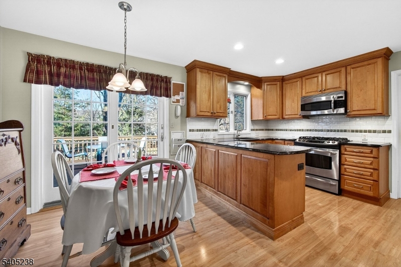 6 Phoenix Drive Mendham, NJ 07945 - Photo 2 of 23 a kitchen with stainless steel appliances granite countertop a stove top oven a sink dishwasher a dining table and chairs with wooden floor