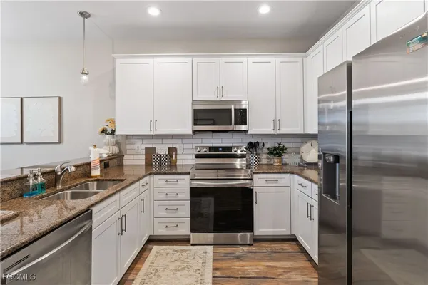 a kitchen with stainless steel appliances granite countertop a stove a sink and a refrigerator
