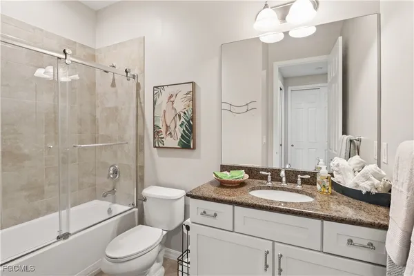 a bathroom with a granite countertop sink toilet a mirror a shower and a bathtub