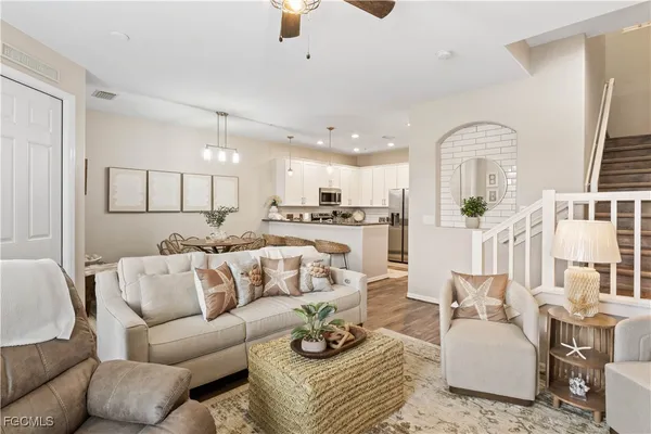 a living room with furniture kitchen view and a chandelier