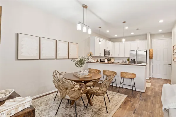 a dining room with stainless steel appliances kitchen island granite countertop a dining table chairs and a refrigerator