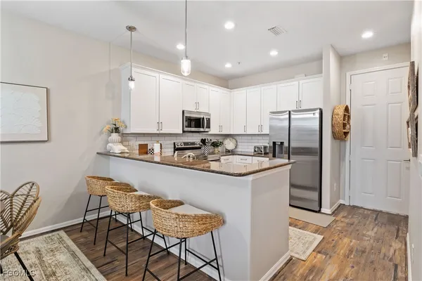 a kitchen with stainless steel appliances a refrigerator a stove a sink and chairs