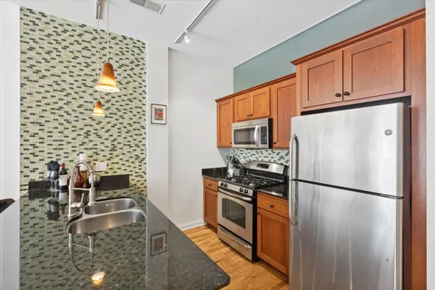 a kitchen with stainless steel appliances granite countertop a refrigerator a stove a sink and a microwave