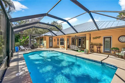a view of swimming pool with chairs and tables in patio