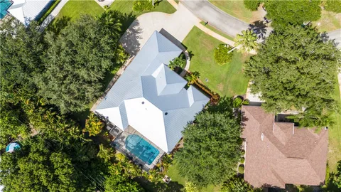 an aerial view of a house with a yard and trees all around