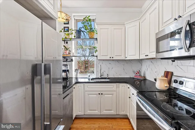 a kitchen with stainless steel appliances granite countertop a sink a stove cabinets and a window