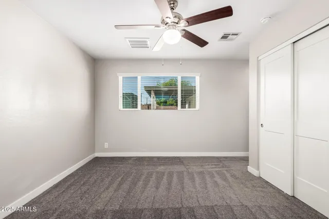 an empty room with windows and fan