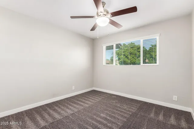 an empty room with a window and a fan