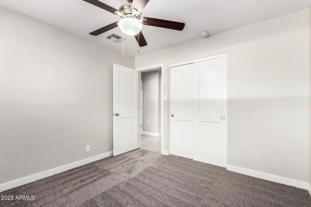 an empty room with closet and a ceiling fan