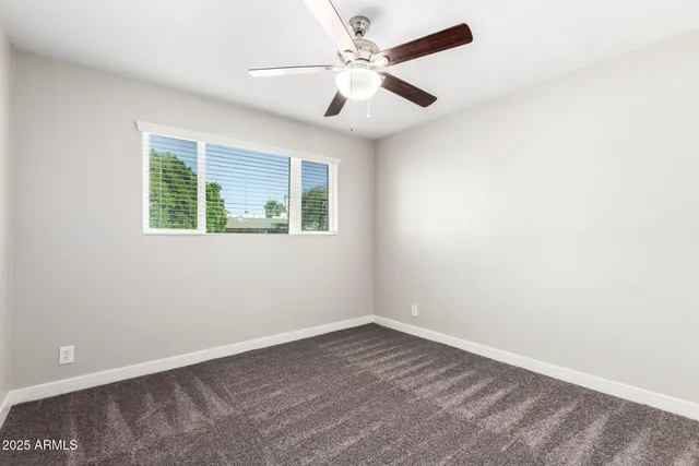 an empty room with a window and a fan