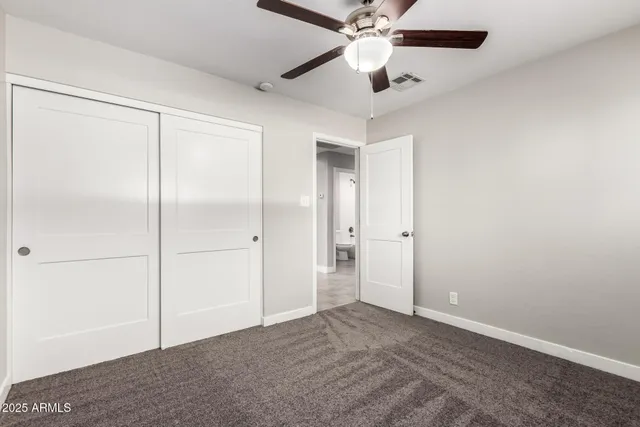 an empty room with closet and a chandelier fan