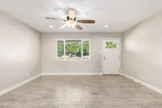 an empty room with windows and fan