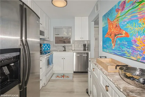 a kitchen with stainless steel appliances a sink a stove a refrigerator and cabinets