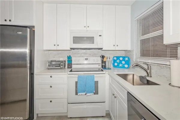 a kitchen with granite countertop white cabinets and stainless steel appliances