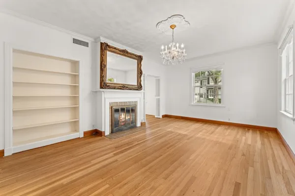 a view of a livingroom with wooden floor fireplace and a window