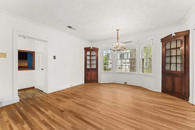 a view of an empty room with window and wooden floor