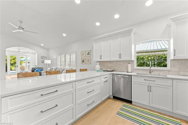 a kitchen with white cabinets and window