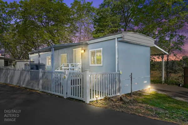 a view of a house with a small yard plants and large tree