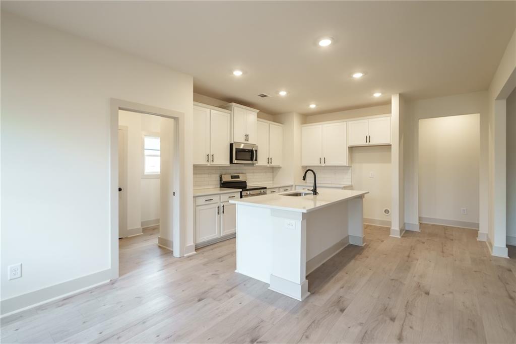 205 Squirrel Run Good Hope, GA 30641 - Photo 13 of 50 a large kitchen with a center island wooden floor stainless steel appliances and cabinets