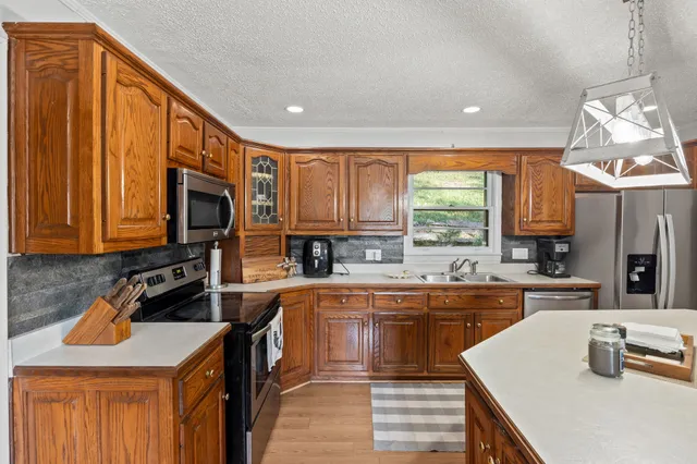 a kitchen with stainless steel appliances granite countertop a sink stove microwave and refrigerator