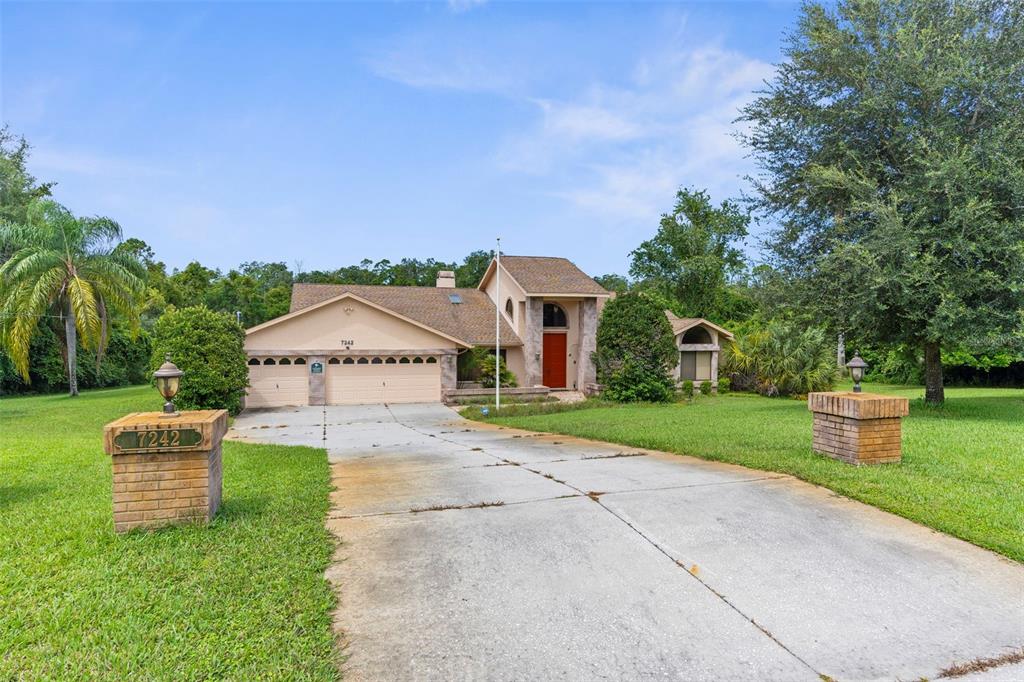 a view of a house with a big yard plants and large trees