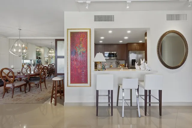 a kitchen with stainless steel appliances granite countertop a dining table chairs and a refrigerator