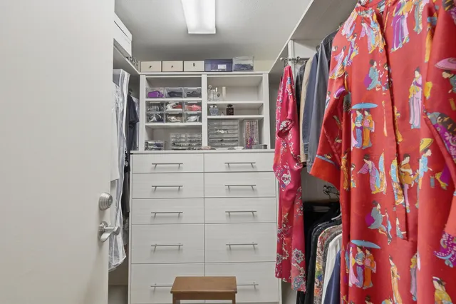 a view of walk in closet with clothes and shoes