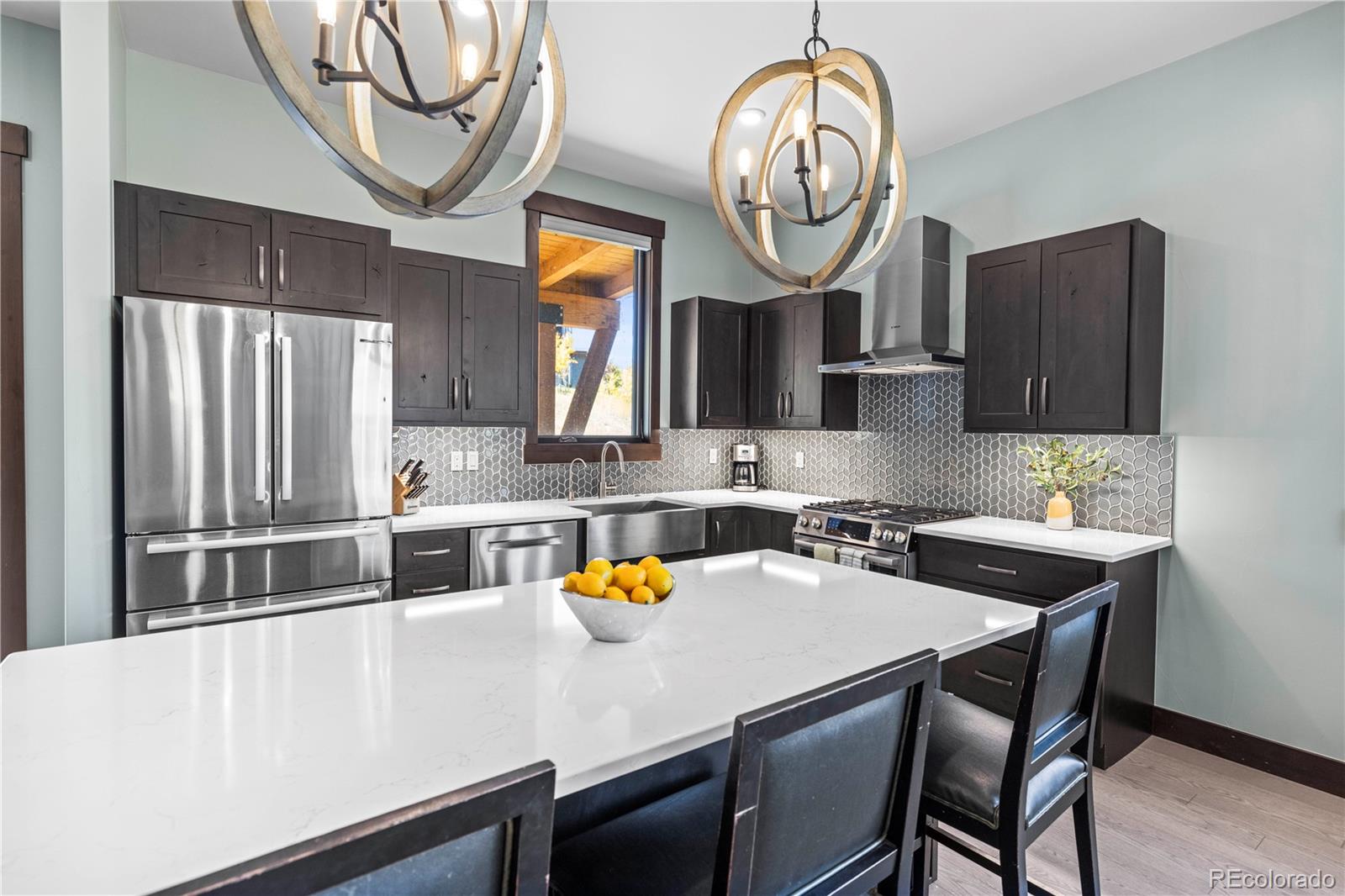 143 Beasley Road Silverthorne, CO 80498 - Photo 11 of 40 a kitchen with stainless steel appliances granite countertop a sink a stove a oven a dining table and chairs with wooden floor
