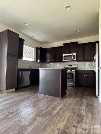 a kitchen with stainless steel appliances granite countertop a stove a sink and a refrigerator