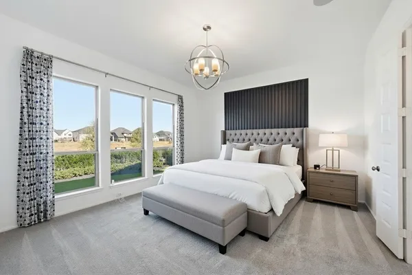 a spacious bedroom with a bed and a flat tv screen on dresser