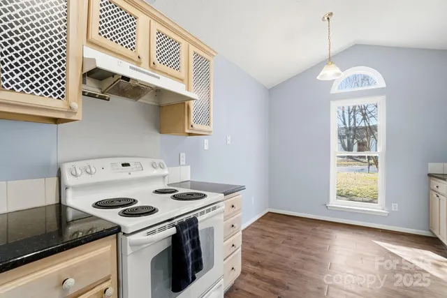 a kitchen with a stove and a white wooden cabinets