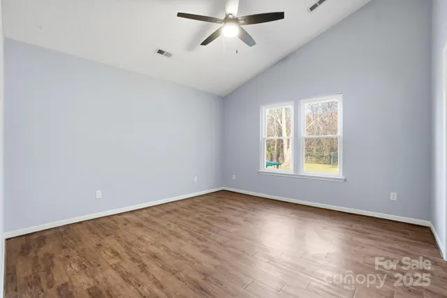 an empty room with windows and ceiling fan