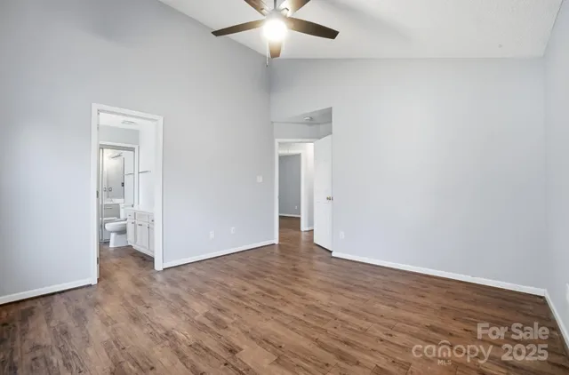 an empty room with wooden floor and a ceiling fan