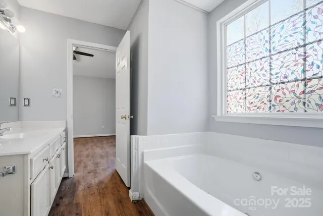 a bathroom with a bathtub a sink a vanity and a window