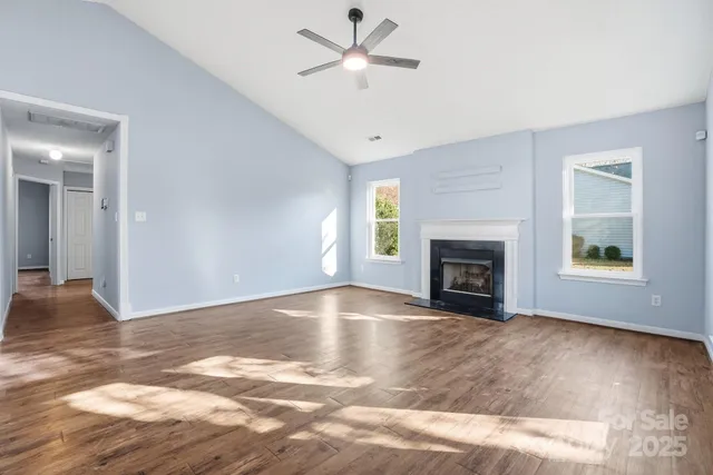 a view of empty room with a fireplace and wooden floor