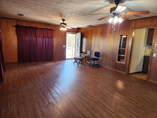 a view of empty room with wooden floor and fan