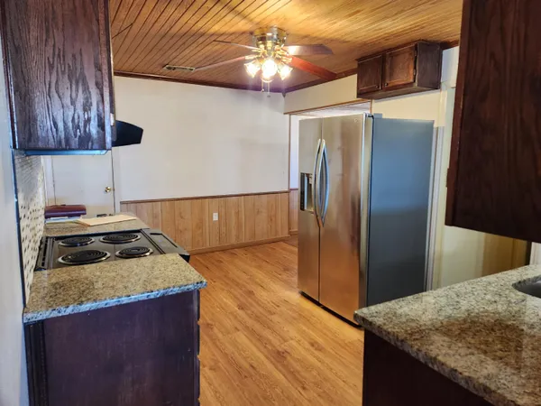a kitchen with granite countertop a stove top oven microwave and cabinets