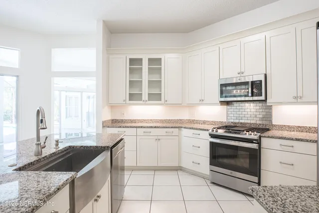 a kitchen with granite countertop a stove sink and microwave