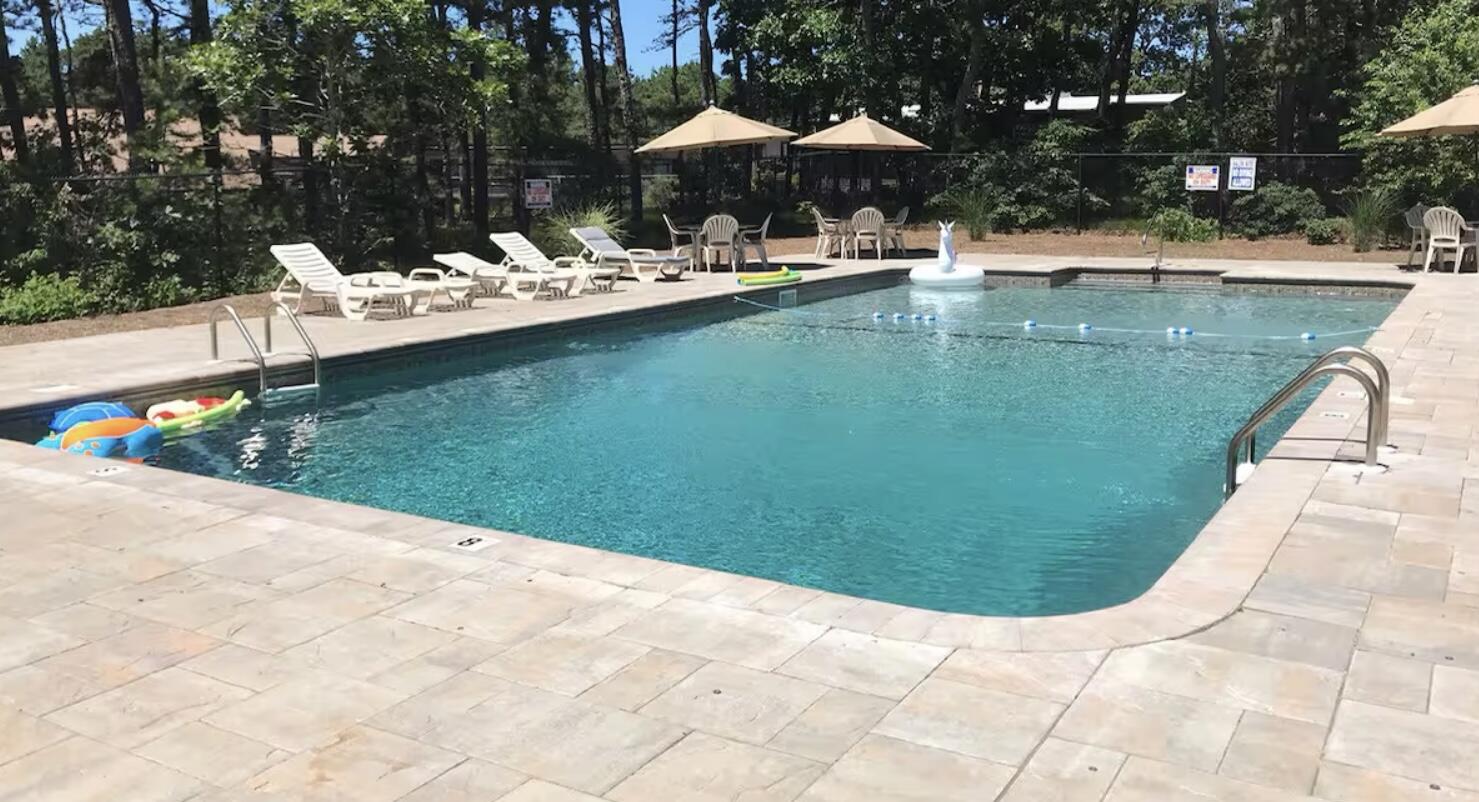 2032 State Hwy Route, Unit F/ (6) Wellfleet, MA 02667 - Photo 4 of 37 a view of a swimming pool with a table and chairs under an umbrella