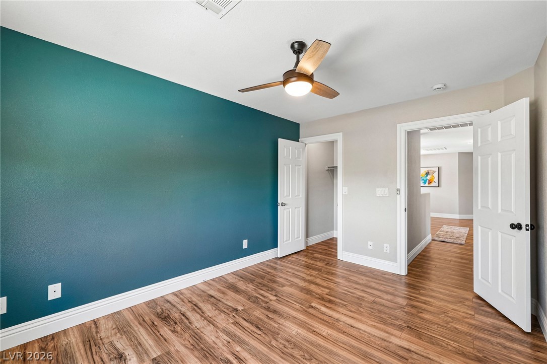 1176 Butternut Ranch Court Henderson, NV 89052 - Photo 25 of 60 Laminate wood flooring grounds this naturally illuminated bedroom with a modern ceiling fan.