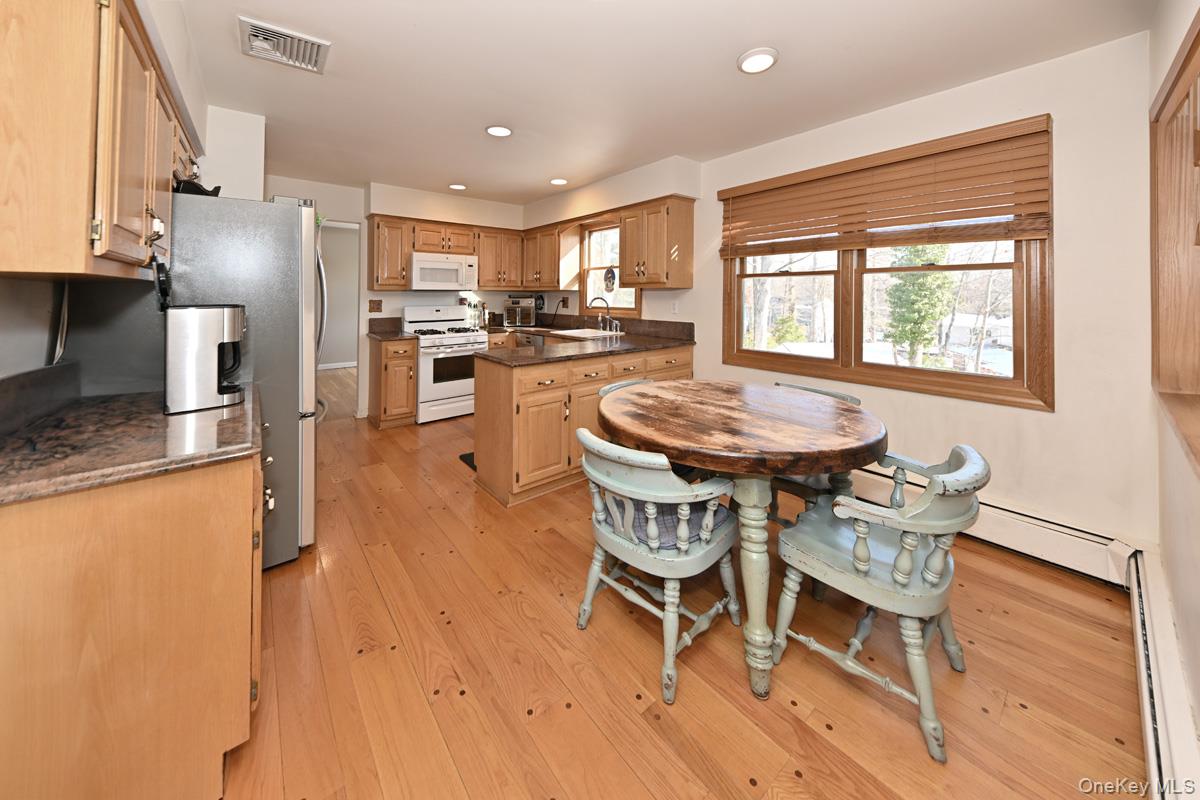 7 Lexington Road New City, NY 10956 - Photo 11 of 36 Kitchen with white appliances, light wood-style floors, a baseboard heating unit, recessed lighting, and dark stone counters