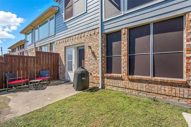 a view of brick house with large windows and wooden fence