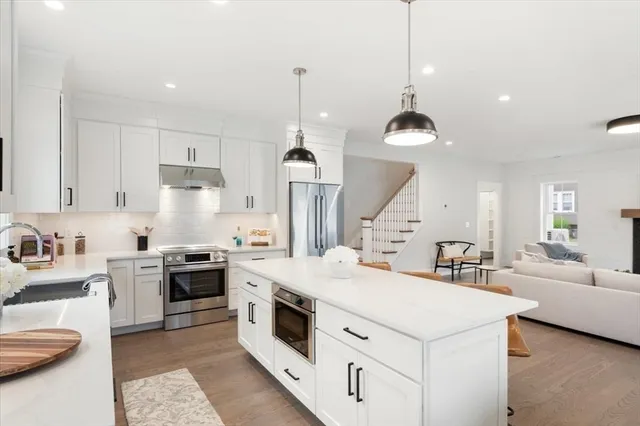a kitchen that has a lot of white cabinets and stainless steel appliances