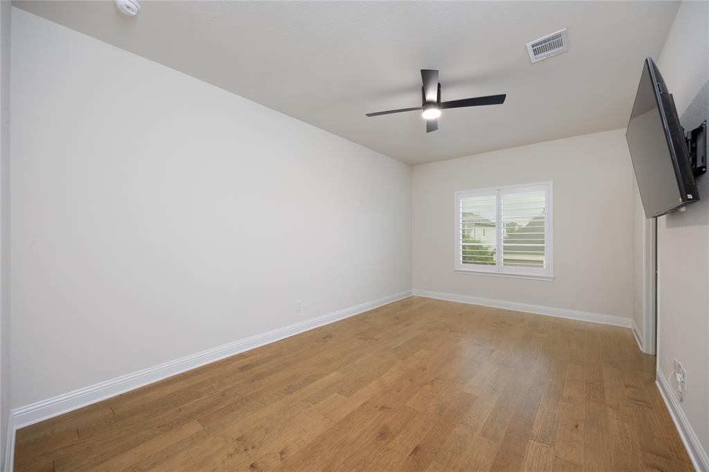 918 Sydney Lane Allen, TX 75013 - Photo 27 of 40 This bright Bed room 4 features hardwood flooring, a ceiling fan with integrated lighting, and a window with white louvered shutters