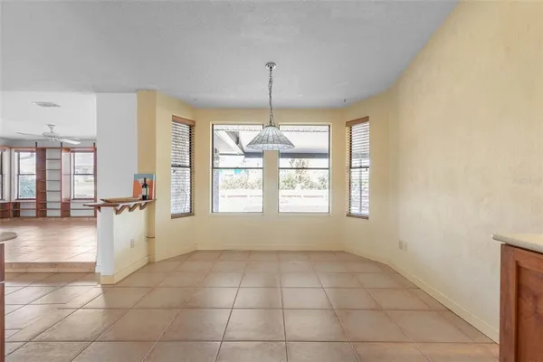 a view of an empty room with wooden floor and a ceiling fan