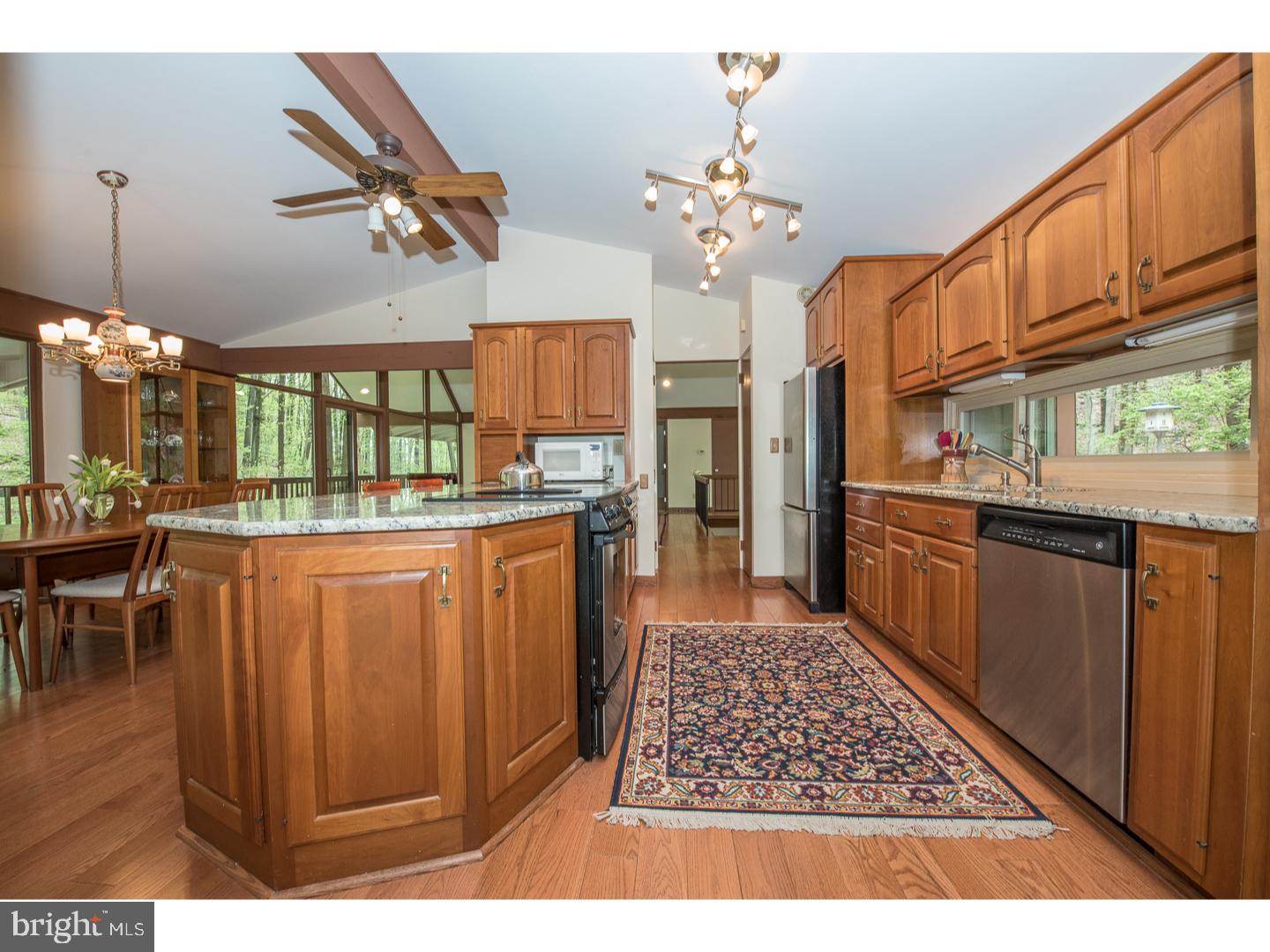 597 Upper Weadley Road Wayne, PA 19087 - Photo 7 of 25 a open kitchen with stainless steel appliances granite countertop a stove top oven a dining table and chairs with wooden floor