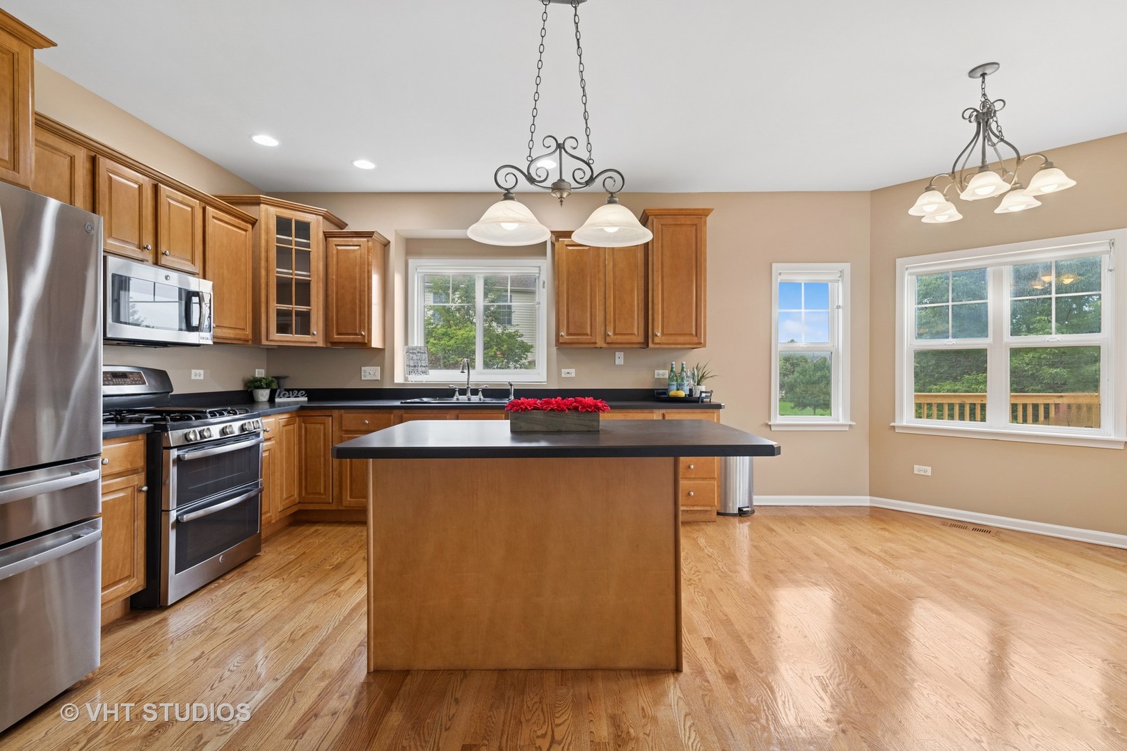12804 Stellar Lane Plainfield, IL 60585 - Photo 13 of 37 a kitchen with stainless steel appliances granite countertop a stove a sink dishwasher a refrigerator and a dining table with wooden floor