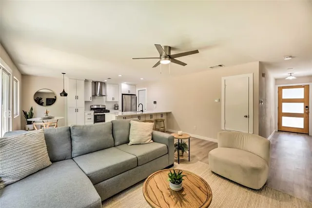 a living room with furniture kitchen view and a wooden floor