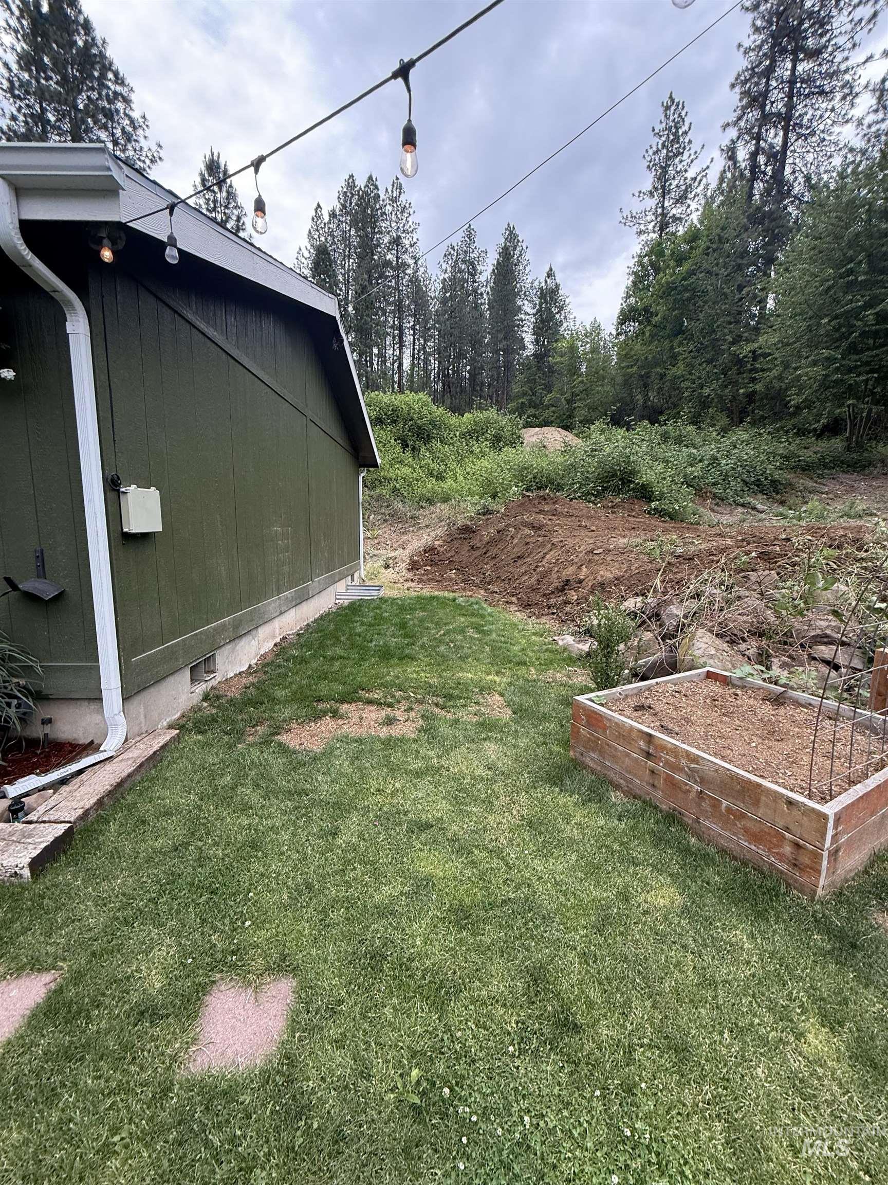 174 Konkolville Road Orofino, ID 83544 - Photo 32 of 43 Side yard featuring a manicured lawn, string lighting, and a raised garden bed